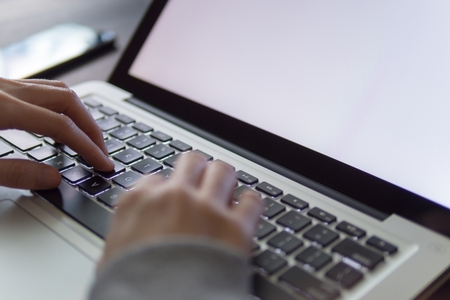 Young woman using a laptop in office, typing on laptop.の写真素材