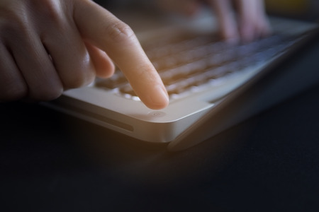 Finger of woman press power button on laptop.の写真素材