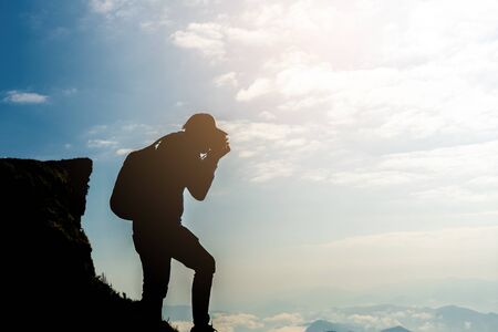Man photographer with backpack and camera taking photo of sunrise mountain landscape for travel or lifestyle concept.の写真素材