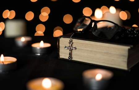 Rosary on holy bible with candlelights and bokeh lights background.の写真素材