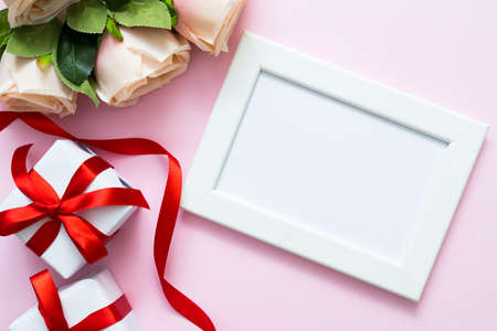 Top view of white frame with copy space , roses and gift boxes on pink background. Sweet Valentine...