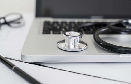 Doctor desk with stethoscope on laptop for health care and medical concept.の写真素材