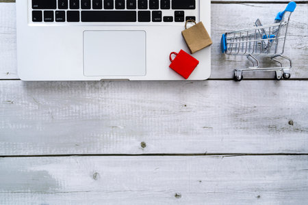 Shopping online concept with top view laptop, paper bags and cart with copy space for text.の写真素材