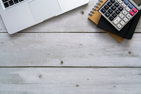 Laptop, calculator and notebook on white wood table with copy space. Top view of business financial concept.の写真素材