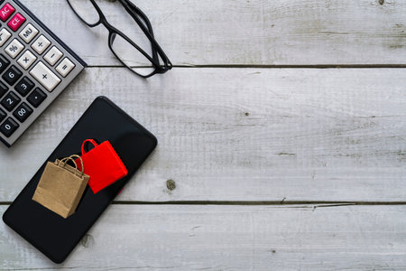 Online shopping concept with shopping paper bags on smartphone, glasses and calculatorの写真素材