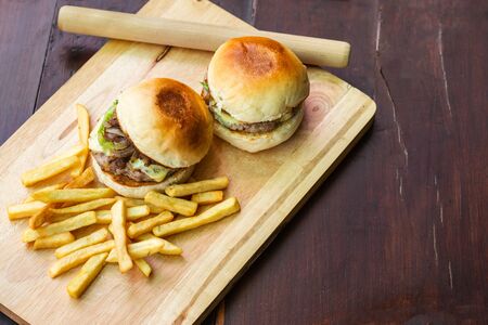 Top image of burgers and fries on a wooden cutting board Is a food that is convenient, uncomplicated and can cook at home.の写真素材