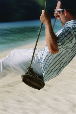 Man on a swing outdoors at the beach (blur)の写真素材