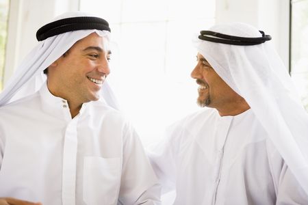 Two men sitting indoors talking and smiling (high key)の写真素材