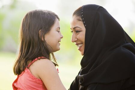 Mother and daughter outdoors in park embracing and smiling (selective focus)の写真素材
