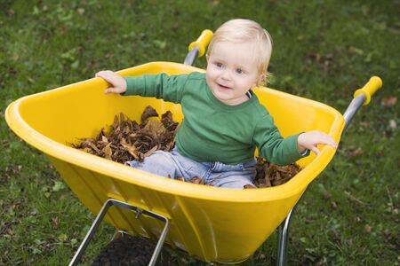  outdoors sitting in wheelbarrow smiling (selective focus)の写真素材