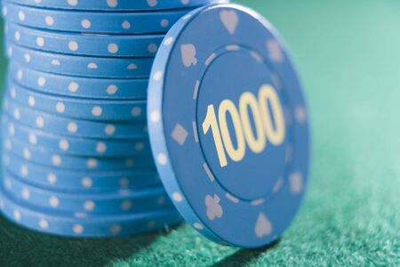 Poker chips piled on a poker table with one thousand chip showing (close up/selective focus)の写真素材