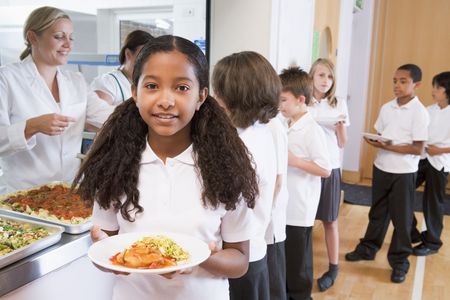 Students in cafeteria line with one holding her healthy meal and looking at camera (depth of field)の写真素材