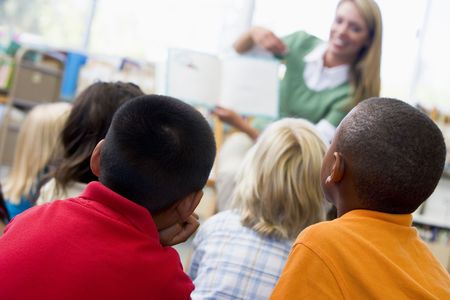 Students in class with teacher reading to them (depth of field)