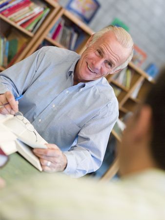 Two men in library with notepads talking (selective focus)の写真素材
