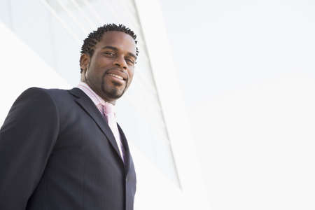 Businessman standing outdoors by building smiling