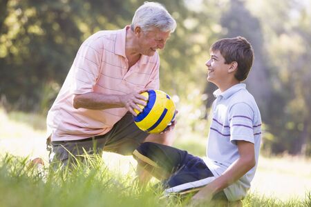 Grandfather and grandson at a park with a ball smilingの写真素材