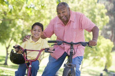 Grandfather and grandson on bikes outdoors smilingの写真素材