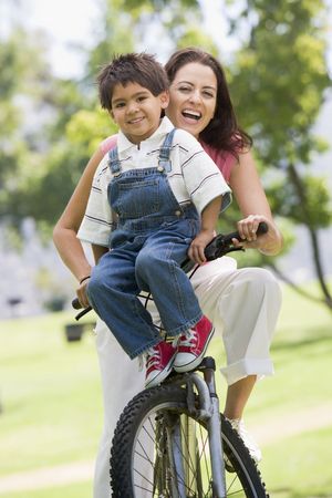 Woman and young boy on a bike outdoors smilingの写真素材