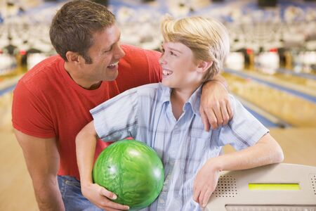 Man and young boy in bowling alley holding ball and smilingの写真素材