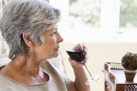 Woman in living room with glass of wineの写真素材