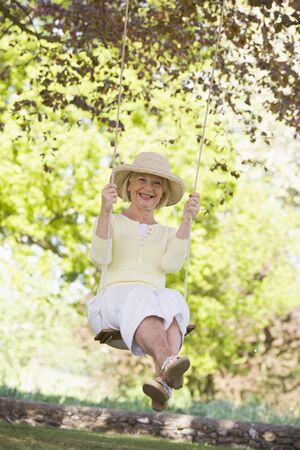 Woman on a swing outdoors smilingの写真素材
