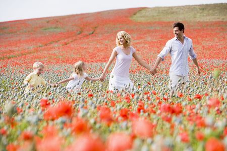 Family walking in poppy field holding hands smilingの写真素材