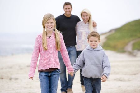 Family walking at beach holding hands smilingの写真素材