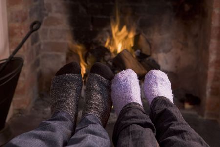 Couple's feet warming at a fireplaceの写真素材