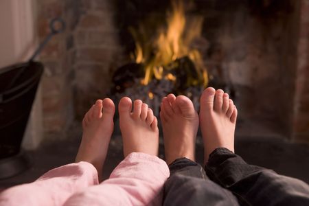 Children's feet warming at a fireplaceの写真素材