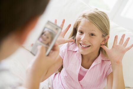 Young boy taking picture of smiling young girl with camera phone indoorsの写真素材