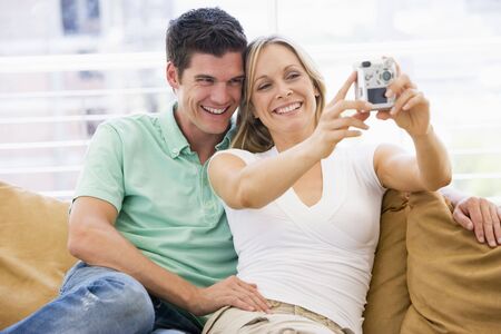 Couple in living room with digital camera smilingの写真素材