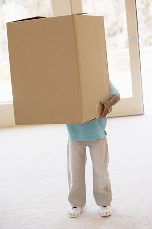 Young boy holding box in new homeの写真素材