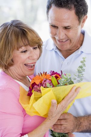 Husband and wife holding flowers and smilingの写真素材