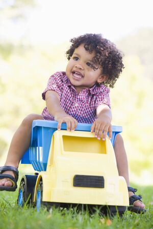 Young boy playing on toy dump truck outdoorsの写真素材