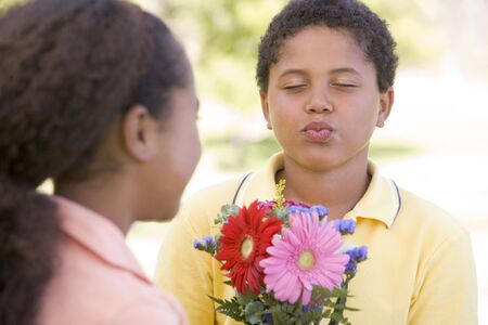 Young boy giving young girl flowers and puckering upの写真素材