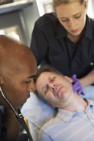 Paramedic using stethoscope on patient in ambulanceの写真素材