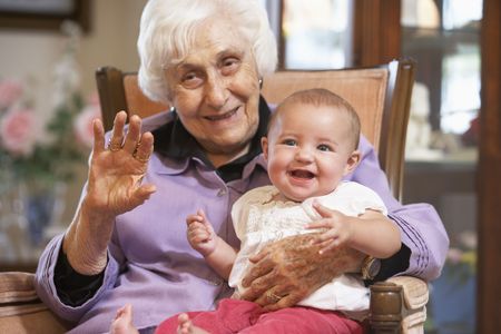 Grandmother holding her granddaughter on lapの写真素材