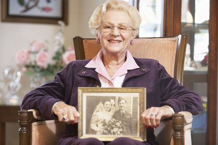 Senior woman holding an old wedding photoの写真素材