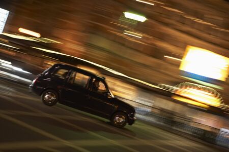 Taxi Driving Through Night Time Streetの写真素材