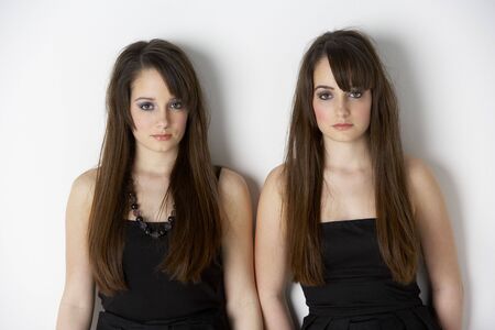 Studio Portrait Of Fashionably Dressed Twin Teenage Girlsの写真素材