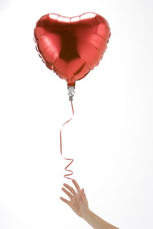 Hand Letting Go Of Heart Shaped Balloonの写真素材