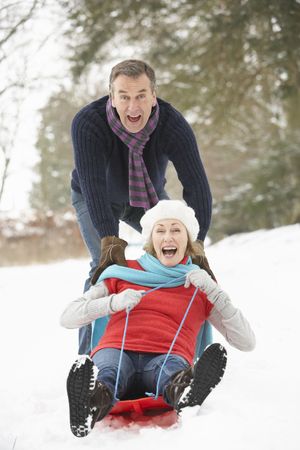 Senior Couple Sledging Through Snowy Woodlandの写真素材