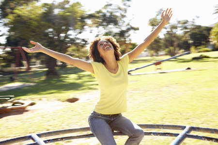 Young Woman Riding On Roundabout In Parkの写真素材