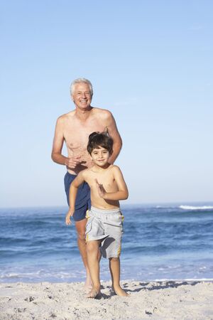 Grandfather, Father and Grandson Running Along Beachの写真素材