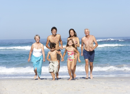 Three Generation Family On Holiday Walking Along Beachの写真素材