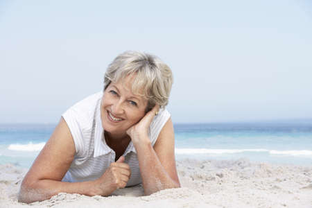 Senior Woman Relaxing On Sandy Beachの写真素材