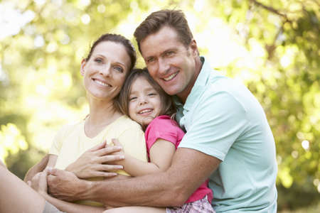 Family Sitting On Tree In Parkの写真素材