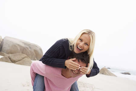 Man Giving Woman Piggyback On Winter Beachの写真素材