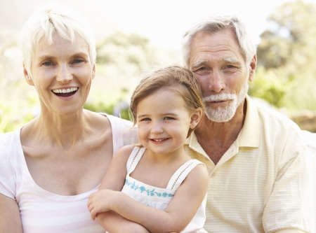 Grandparents And Granddaughter Relaxing In Gardenの写真素材