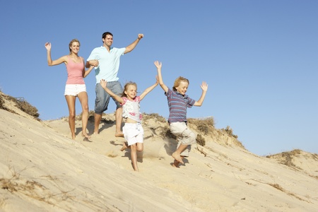 Family Enjoying Beach Holiday Running Down Duneの写真素材